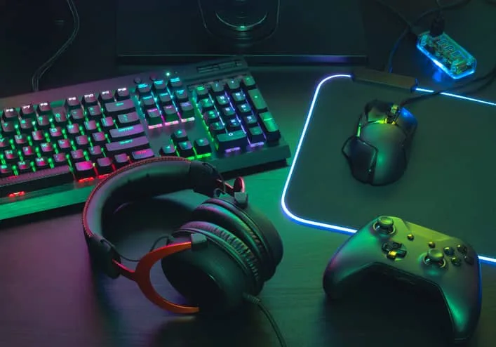 Conceito do espaço do trabalho do Gamer, vista superior uma engrenagem do jogo, rato, teclado, manche, auriculares, manche móvel, no auscultadores da orelha e na almofada de rato no fundo preto da tabela.