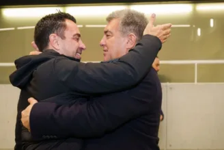 Técnico Xavi e o presidente Joan Laporta se abraçam após o anúncio da permanência do ídolo no Barcelona