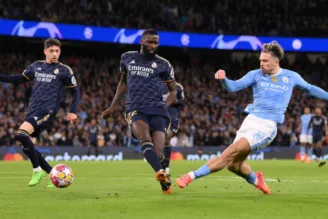 Jack Grealish, do Manchester City, atira sob pressão de Antonio Ruediger, do Real Madrid, durante o jogo da segunda mão dos quartos-de-final da UEFA Champions League entre Manchester City e Real Madrid CF, no Etihad Stadium, em 17 de abril de 2024, em Manchester, Inglaterra