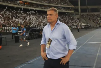 Na imagem, Diego Aguirre tem mãos na cintura com torcedores do Botafogo ao fundo