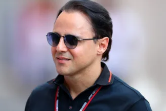 Na imagem, Felipe Massa está de óculos escuros com camisa da F1 e um crachá