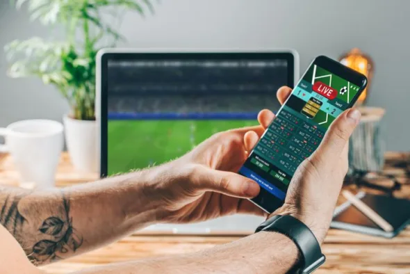 pessoa segurando celular apostas esportivas